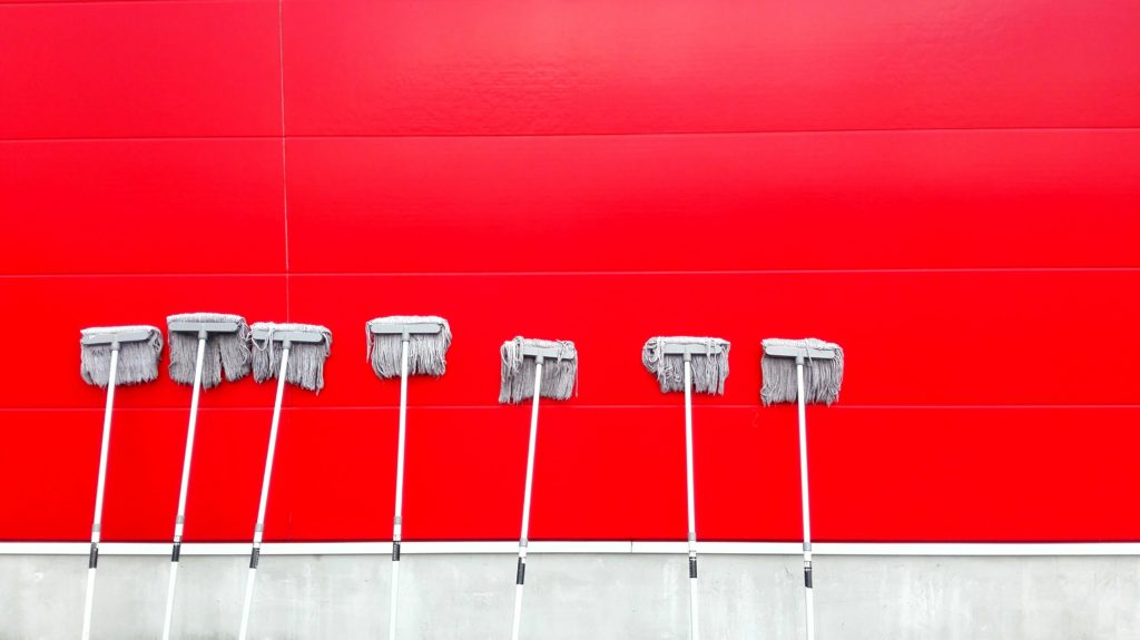 White mops leaning up against a bright red wall