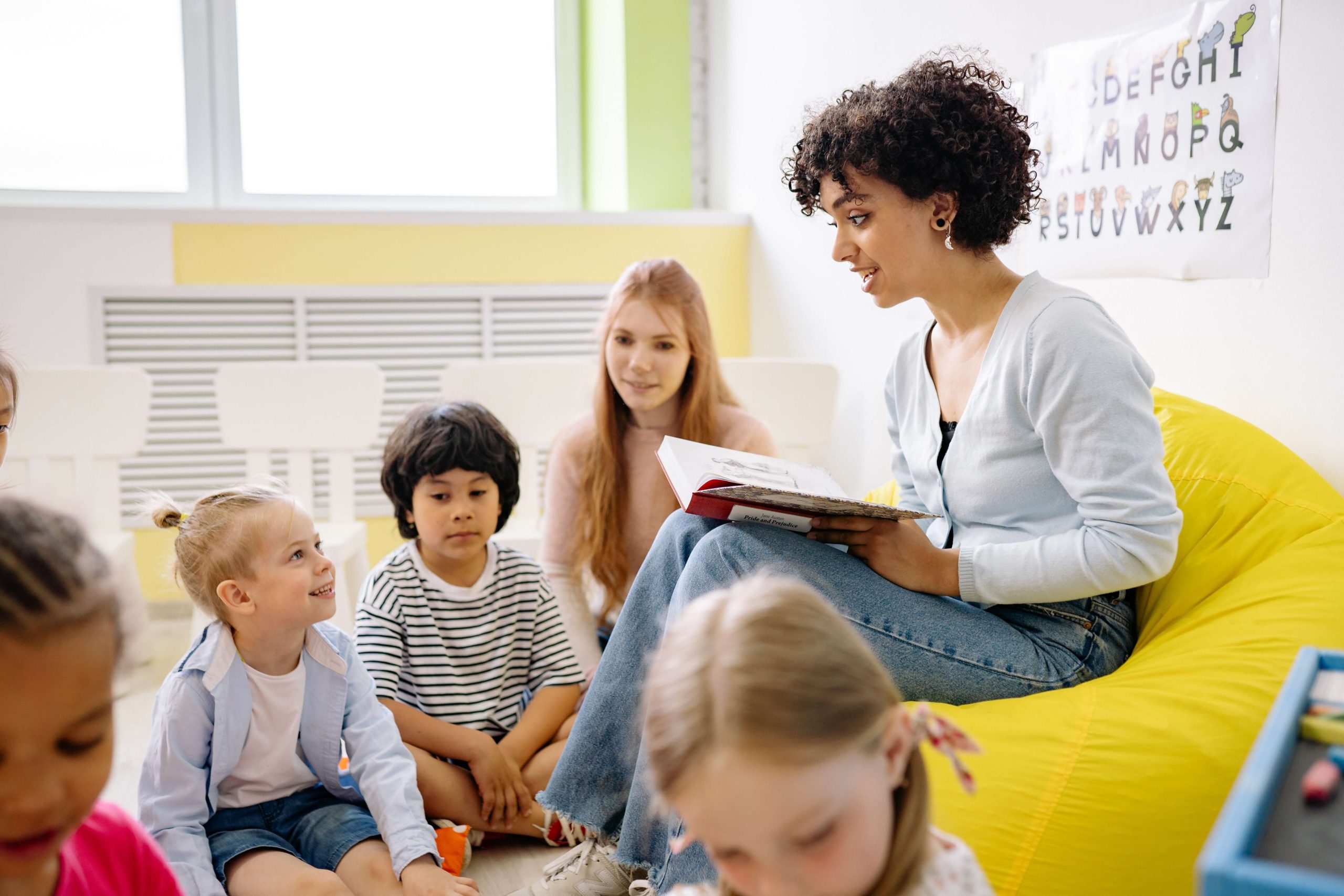 A teacher on a fixed length pay period reads a book to a group of students