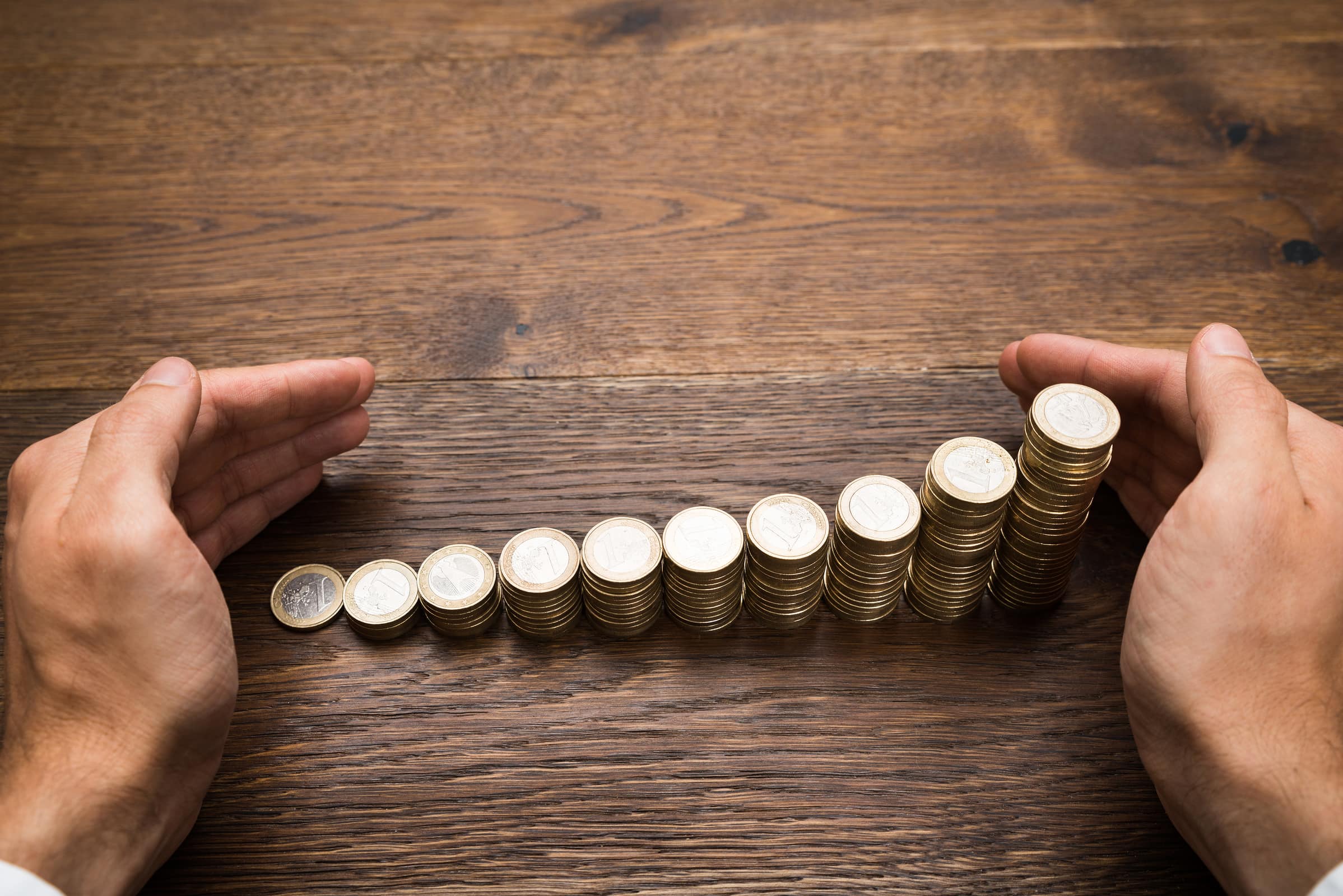 Close-up Of A Businessman's Hand Protecting Stack Of Coins